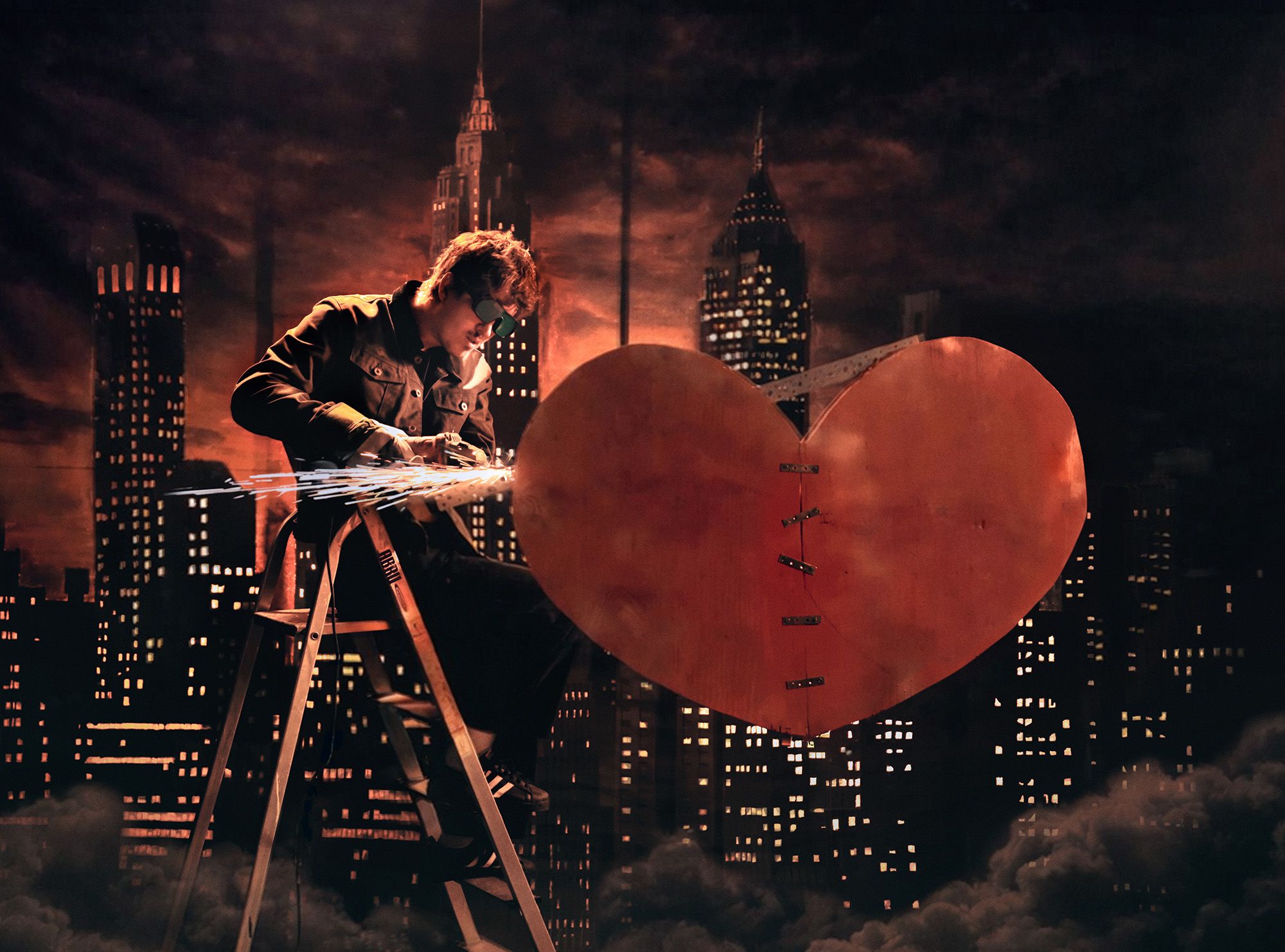 Arthur Hill sat on top of a ladder fabricating a stitched together heart infront of a city skyline